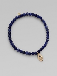 The open hand or hamsa, a symbol of protection to many cultures, is depicted in diamonds set in 14k yellow gold with a sapphire center, and hangs on a strand of deeply hued sodalite beads. Diamonds, 0.04 tcw Sapphire Sodalite 14k yellow gold Diameter, about 2 Charm length, about ½ Stretch cord Imported