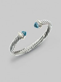 From the Silver Classics Collection. The signature Yurman cable bangle, capped with faceted blue topaz domes and accents of 14k gold. Blue topaz Sterling silver and 14k yellow gold Cable, 7mm Diameter, about 2¼ Imported