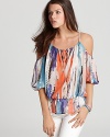 A billowy silhouette, cutout shoulders and abstract print infuse this eclectic GUESS top with carefree summer style.