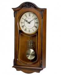 A mark of elegance. This stately wall clock by Bulova features a sturdy solid wood case with walnut finish accented by decorative carvings. White dial features Roman numerals and two hands; gold tone pendulum protected by glass lens. Plays Westminster melody on the hour.